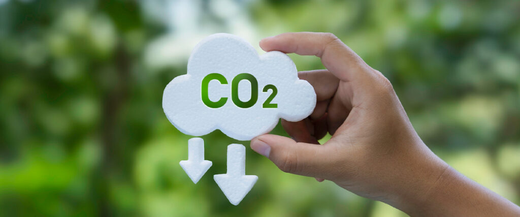 A hand holds a cloud that says CO2 with downward arrows falling from it